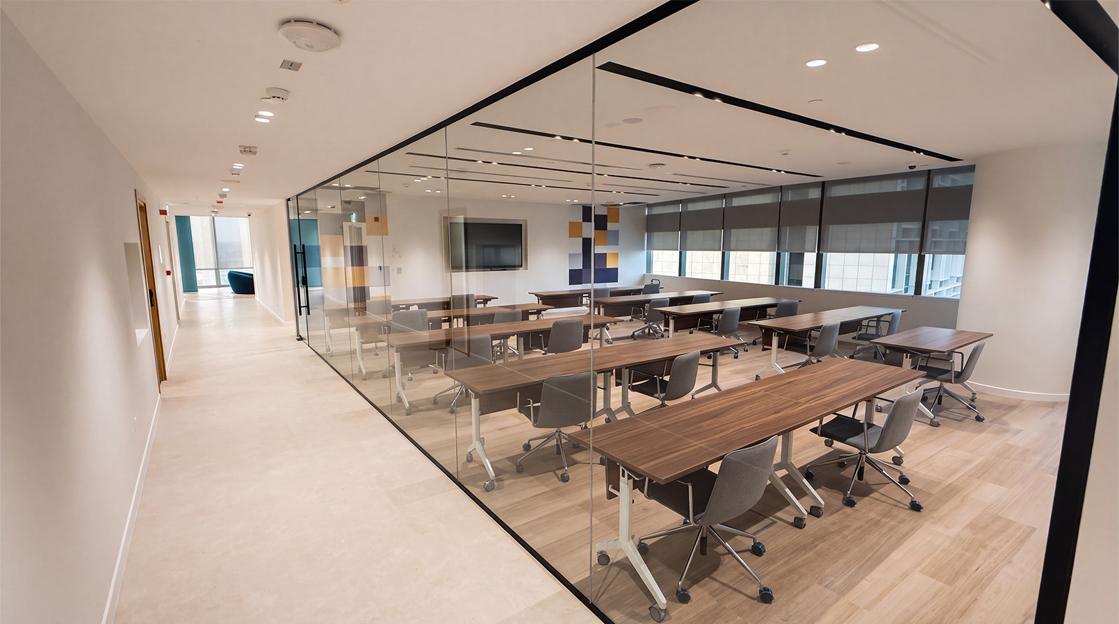 Glass-fronted learning room with rows of tables and chairs.