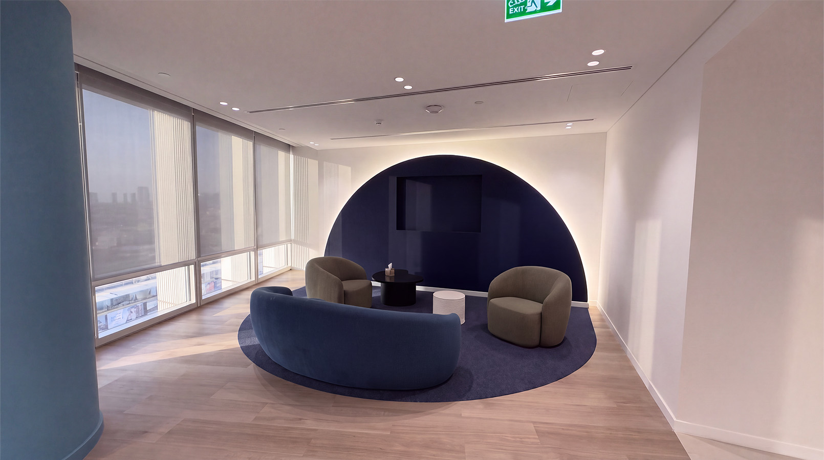 Curved blue sofa and armchairs beside a circular wall recess.